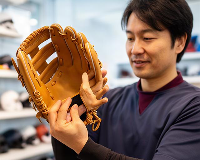 松戸市のグラブ専門店で大人の男性が軟式グラブを手にはめて確かめている様子